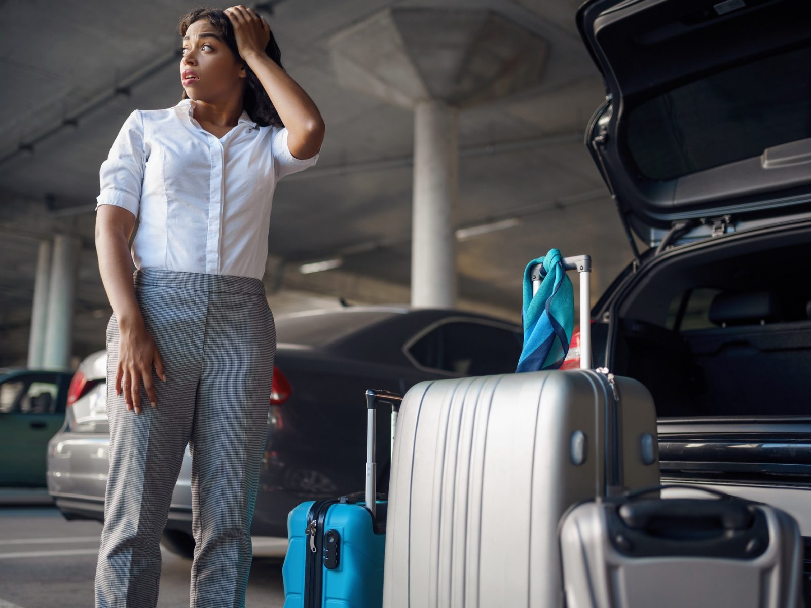 Young woman with suitcases in a panic, car parking